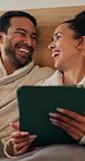 Tablet, talking and couple on bed in house with browsing social media, internet or website. Relax, digital technology and man with woman in bedroom for reading blog on app together in apartment.