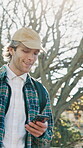 Student, walking and man with phone, park and communication with contact on social media or website. Reading, funny message and happy person in nature, travel and scroll college updates on mobile