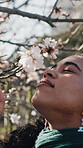 Smelling, flowers and woman on break in nature, laughing and relax on spring vacation and low angle. Outdoor, fresh air and happy person with floral plants, calm and peaceful holiday in garden