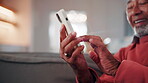 Hands, old man and smile at house with phone, social media or browsing website for online bingo. Senior person, relax and scroll in home with mobile, internet search and download games for retirement