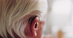 Senior, woman and ear with hearing aid for audio, sound or awareness for balance in house. Elderly, female person or retirement with medical senses for speech, noise or treatment in nursing home