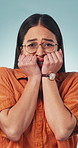 Face, scared and woman in studio with fear, horror movie and reaction to dangerous situation. Portrait, person and afraid expression for frightening news, witness robbery and panic on blue background