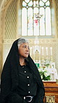 Thinking, funeral and woman in church for memory, reflection or nostalgia with bereavement. Sad, perspective and mature person at memorial service for mourning, respect and farewell in holy building.