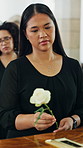 Thinking, sad and woman at casket with rose, remember and grieving past with mourning. Reflection, coping and person in church with flower, bereavement and emotional flashback at memorial service.