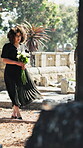Thinking, sad or woman in cemetery with bouquet, remember or grieving past with mourning. Reflection, windy or person at gravestone with flowers, bereavement or emotional flashback at memorial visit.