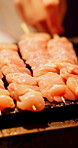 Food, skewer and hands with chicken on grill in Japan for recipe, cuisine or cooking. Person, chef or kebab with meat sticks, meal prep or Yakitori in market street for culinary art, snack or dinner