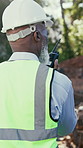 Construction, back or black man on site with radio, task brief or inspection update in chat. Bokeh, tech or mature engineer with walking, progress feedback or project coordination in communication.