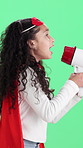 Girl, superhero and cosplay with megaphone on green screen for role play on a studio background. Child, kid or talking with bullhorn or loudspeaker in hero costume for dress up or announcement