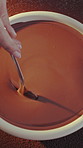 Baking, hands and mixing chocolate on table for mousse dessert, gourmet treat and creamy recipe. Baker, person and ganache sauce for cake filling, homemade pudding and ingredients preparation in home