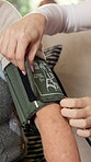 Caregiver, hands or people with blood pressure cuff, screening or heart health exam in elderly care. Medical, nurse or senior person with tech, hypertension monitor or vital signs in retirement home.