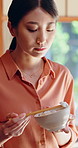 Asian woman, eating and food at house with chopsticks, healthy rice and traditional meal for lunch. Female person, bowl and utensils in home for brunch, nutrition snack and authentic Chinese cuisine