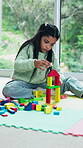 Balance, building blocks and girl child on floor in home for development of motor skills. Concentration, growth and wooden toy with kid on play mat in apartment for coordination, creative or game