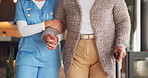 Senior, woman and cane in home with physiotherapist, walking exercise or help for stroke recovery. Medical worker, support and old person in house with mobility aid, holding hands and rehabilitation.