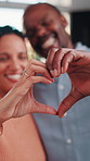 Happy, home and love with heart hands for relationship care, bonding or commitment together. Man, woman or smile with like emoji, shape or symbol for health, wellness or romantic gesture in house