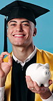 Face, graduation and man in studio with piggy bank for education, scholarship and college fund. Graduate, okay sign and person with savings for university, learning or milestone on blue background