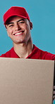 Box, happy and face of delivery man in studio with confidence for export courier service. Smile, package and portrait of supply chain worker with cardboard parcel for distribution by blue background.