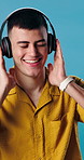 Dance, happy and man with headphones in studio for good mood, positivity and energy on weekend. Rhythm, dancer and person with streaming subscription for music, playlist and radio on blue background