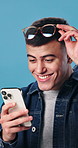 Shock, phone and man in studio with good news, update or notification of winning gambling. Prize, surprise and person with cellphone for financial bonus with online competition by blue background.