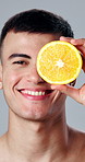 Skincare, lemon and face of man in studio for beauty, health and natural cosmetic routine. Happy, nutrition and portrait of person with citrus fruit for dermatology treatment by white background.