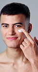 Studio, face and happy man with lotion for skincare or grooming routine on a gray background. Portrait, male person or facial treatment with smile or cream for smooth skin, dermatology or cosmetics