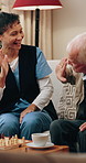 Caregiver, high five and old man in home with chess, competition and winner with fun games. Nurse, celebrate or senior person on sofa with chessboard, contest tactics and checkmate for friendly match