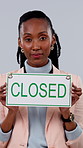 Face, closed or black woman with sign in studio for end of business or closure on a gray background. Portrait, female person or employee with billboard for company bankruptcy, debt or no service