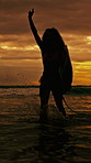 Sunset, woman and walk at beach with surfboard, travel and adventure for summer holiday. Silhouette, person and surfer at sea for freedom, getaway journey and water activity for tropical vacation