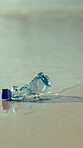 Pollution, litter or bottle on beach with water, trash reduction or climate action in waste management. Plastic, waves or garbage with space, nature protection or eco awareness in ocean conservation.