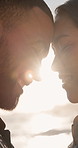 Flare, couple and happy with love at beach for anniversary getaway, laughing and forehead touch. Sunshine, people or bonding at ocean for romantic holiday, healthy relationship or marriage connection