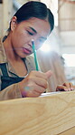 Carpenter, woman and writing measurement in workshop with wood, pencil and ruler for precision. Serious, woodworking and manufacturing in factory for handmade, custom and production of design
