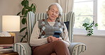 Senior, woman and relax in retirement home with phone, typing text message and browse social media. Elderly person, rest or reading in chair with mobile tech, digital news or online chat notification