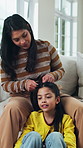 Mother, child and help with hair care on sofa, conversation and bonding together on weekend. Parent, girl and hairstyle in home for beauty routine with grooming, kid talking and family support