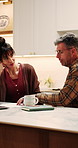 Couple, finance and documents with laptop in kitchen for mortgage payments, bills or investment. Mature man, woman and conversation with paperwork for financial planning or invoices with tech in home