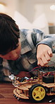 Boy, dad and toy car with cables for engineering or remote control vehicle in home together. Child, kid or learning with father to build robotic transportation for junior mechanic or development