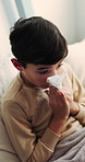 Tissue, sick and child blowing nose in bedroom with allergies, flu or viral infection in home. Sneezing, illness and boy kid with toilet paper for sinusitis, cold or medical virus in bed at house.