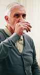 Senior, man and drinking water with medication in home for hydration, medical recovery or treatment. Elderly, male person or pills with beverage for pharmaceutical healthcare or prescription in house