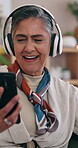 Mature, phone and dancing to music on headphones with positive attitude, energy and happiness. Female person, tech and listen to audio on living room sofa for playlist, subscription and internet