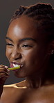 Bite, kiwi and laughing with black woman in studio for antioxidants, health benefits or detox. Eating, fruit and vitamin c with funny person on dark background for beauty, satisfaction or skincare