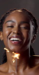 Beauty, face and sparkler with black woman in studio for celebration or satisfaction with results. Fireworks, glow and shine with happy person on dark background for skincare or vitamin c milestone