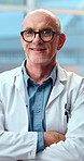 Face, man and doctor in hospital with arms crossed, assistance and medical advice for wellness. Portrait, mature person and surgeon in workplace with smile, positive attitude and healthcare services