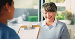 Nurse, clipboard and talking to senior patient in nursing home with kindness, smile and laughing. Medical info, caregiver and old woman with funny question, form and paperwork at consultation