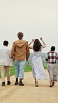 People, friends and walking together in countryside for travel, outdoor adventure or journey. Back view, group or travelers on dirt road, trail or path for weekend getaway, holiday or trip in nature