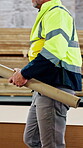 Blueprint, construction and walking with man in workshop for architecture or engineering. Building, industry and project management with person in supply factory for inventory, storage or stock