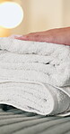 Hotel, hospitality and hands with clean towels, housekeeper and folded linen on bed or fresh laundry. Accommodation, housekeeping and person with cloth pile, hygiene and fabric change in bedroom
