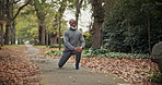 Senior, fitness and black man stretching legs in nature for outdoor exercise or workout preparation. Elderly, male person or getting ready with knee warm up for training, health or wellness in park