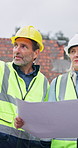 Architect, team and walk at construction site with blueprint, talk or point for building evaluation. Mature people, inspection and document outdoor for infrastructure design, planning or architecture