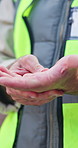 Builder, man and hand pain on construction site with injury, medical problem and massage for relief. Contractor, person and arthritis outdoor with building accident, engineering mistake and crisis.