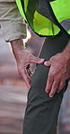 Builder, man and knee pain on construction site with injury, medical problem and massage for relief. Contractor, person and hurt leg outdoor with building accident, engineering mistake and crisis.