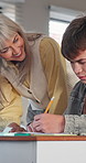 Mature, teacher or writing with student in classroom for education, learning or help in exam. Female person, tutor or assistance with academic learner for test, guidance or understanding in school