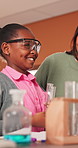 Science, teacher and talking with child in classroom, learn and academic development with education. Educator, advice and kid with safety glasses, woman and happy for chemistry lesson in school